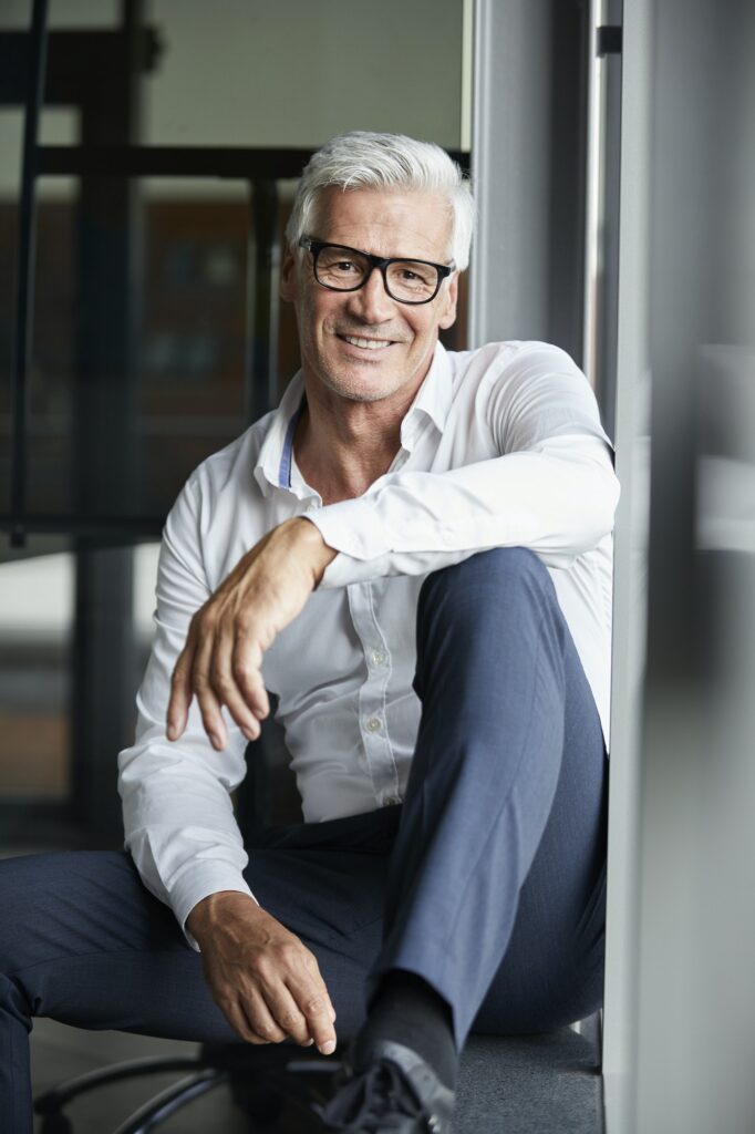 Serene businessman sitting on ground, looking out of window